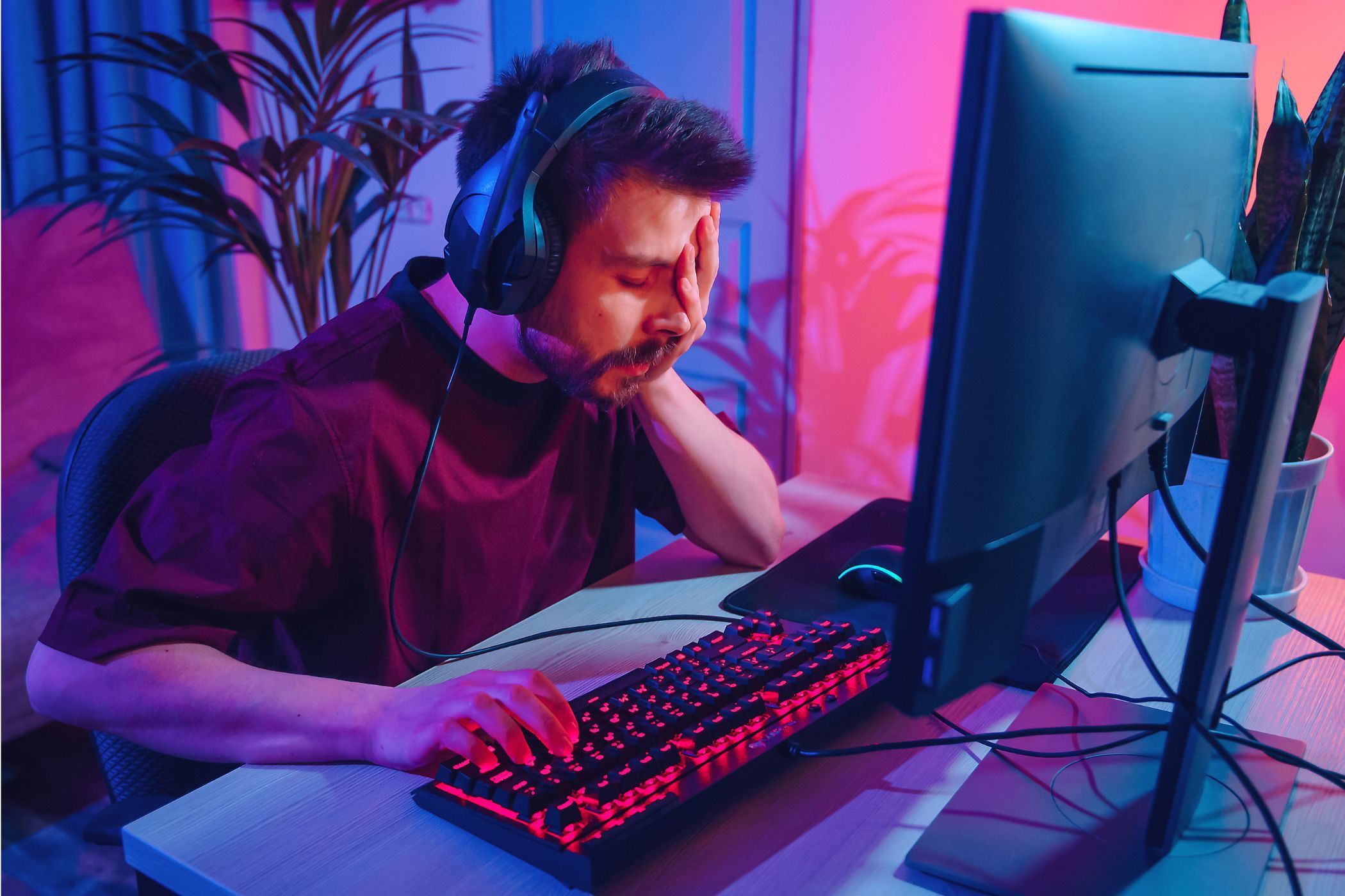 sad computer gamer with hand over face in front of computer